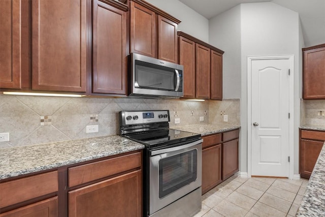 kitchen with decorative backsplash, light tile patterned flooring, light stone counters, and appliances with stainless steel finishes