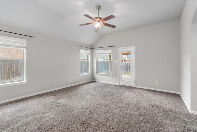 empty room featuring carpet, ceiling fan, a healthy amount of sunlight, and lofted ceiling