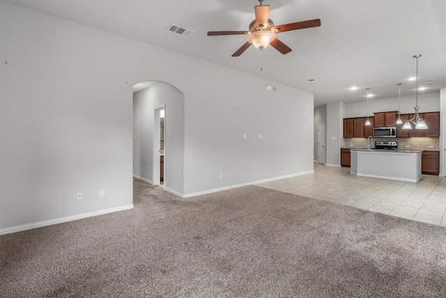 unfurnished living room with light carpet, sink, and ceiling fan