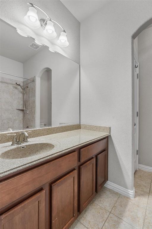 bathroom featuring tile patterned floors, vanity, and a tile shower