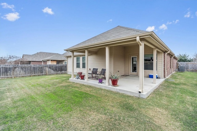 rear view of house with central AC, a patio area, and a lawn