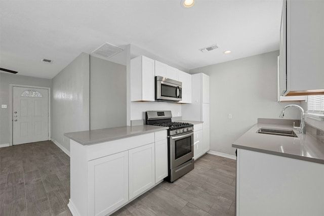 307 E Powell Ln, Austin, TX 78753 - kitchen with white cabinets, sink, kitchen peninsula, and stainless steel appliances
