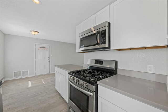 307 E Powell Ln, Austin, TX 78753 - kitchen with white cabinetry, light hardwood / wood-style flooring, and stainless steel appliances