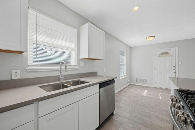 307 E Powell Ln, Austin, TX 78753 - kitchen featuring sink, stainless steel appliances, plenty of natural light, light hardwood / wood-style floors, and white cabinets