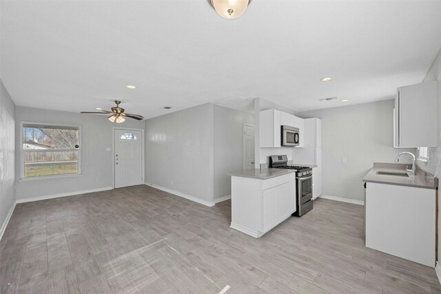 307 E Powell Ln, Austin, TX 78753 - kitchen featuring sink, ceiling fan, light wood-type flooring, appliances with stainless steel finishes, and white cabinetry
