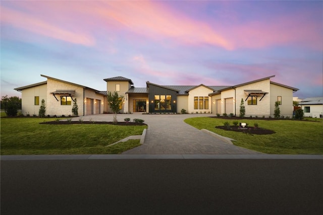 view of front of property with decorative driveway, a yard, an attached garage, a standing seam roof, and metal roof