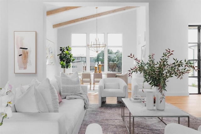 living area featuring plenty of natural light, wood finished floors, beam ceiling, and a notable chandelier