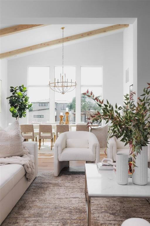 living room with lofted ceiling with beams, wood finished floors, and a chandelier