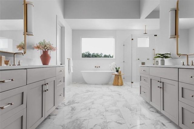 bathroom with a freestanding bath, marble finish floor, two vanities, and a healthy amount of sunlight