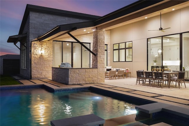 rear view of property featuring a patio, area for grilling, a ceiling fan, an outdoor pool, and outdoor dining space