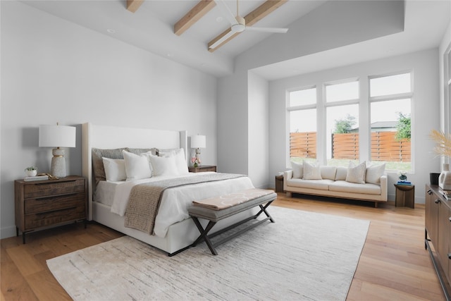 bedroom with vaulted ceiling with beams, light wood-style floors, and a ceiling fan