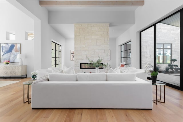 living area featuring light wood-type flooring, beam ceiling, and a fireplace