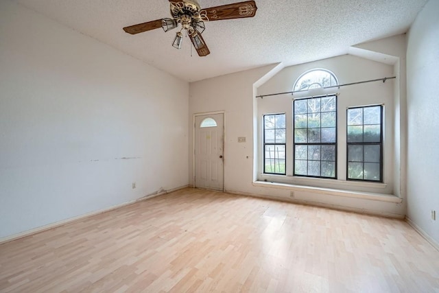 foyer entrance with light wood-type flooring, a textured ceiling, vaulted ceiling, and ceiling fan