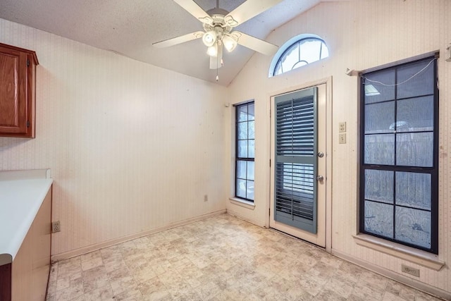 doorway with ceiling fan, a textured ceiling, and vaulted ceiling