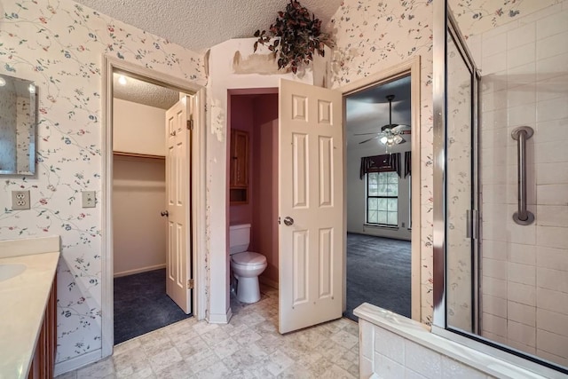 bathroom featuring ceiling fan, a textured ceiling, an enclosed shower, toilet, and vanity