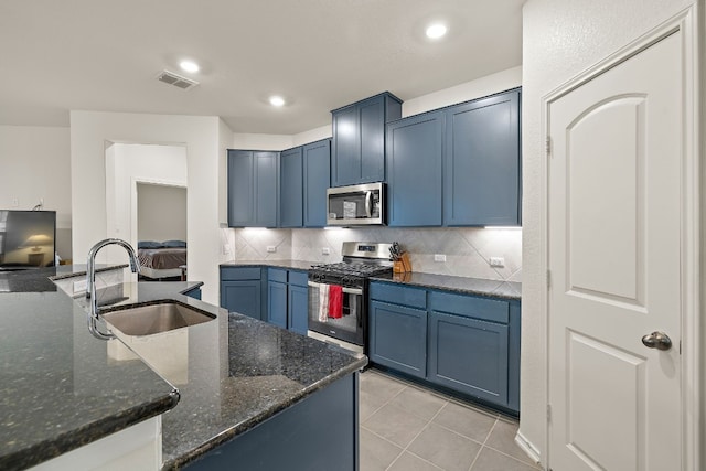 4429 Venticano Pl, Round Rock, TX 78665 - kitchen featuring stainless steel appliances, decorative backsplash, light tile patterned floors, dark stone countertops, and blue cabinetry