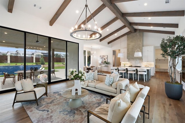 living room with beamed ceiling, wood-type flooring, an inviting chandelier, and high vaulted ceiling