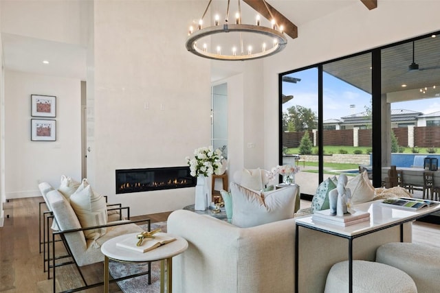 living area with a glass covered fireplace, a notable chandelier, and wood finished floors