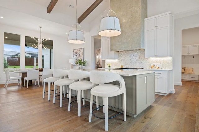 kitchen featuring beamed ceiling, decorative light fixtures, white cabinets, and a kitchen island