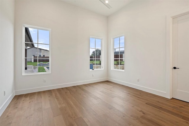 empty room with light hardwood / wood-style floors and a towering ceiling