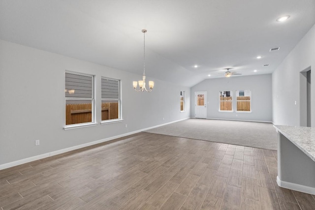 unfurnished living room with ceiling fan with notable chandelier and vaulted ceiling