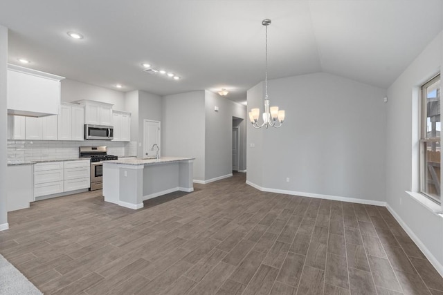 kitchen with decorative backsplash, appliances with stainless steel finishes, vaulted ceiling, white cabinets, and hanging light fixtures