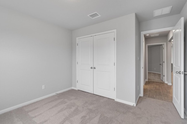 unfurnished bedroom with light colored carpet and a closet