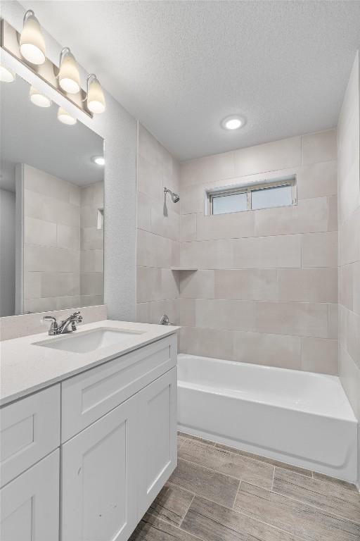 bathroom featuring vanity, tiled shower / bath combo, and a textured ceiling