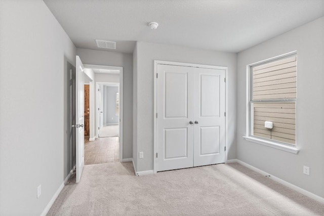 unfurnished bedroom featuring multiple windows, light colored carpet, and a closet