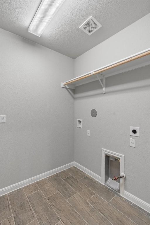 clothes washing area with electric dryer hookup, hookup for a washing machine, and a textured ceiling