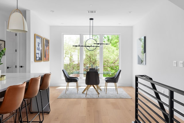 dining space with light wood-type flooring and a notable chandelier