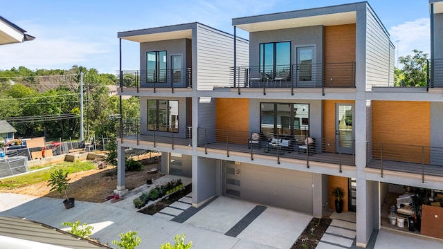 rear view of house featuring a balcony and a garage