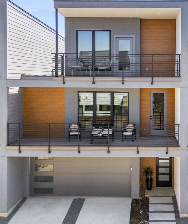 rear view of property featuring a balcony and a garage