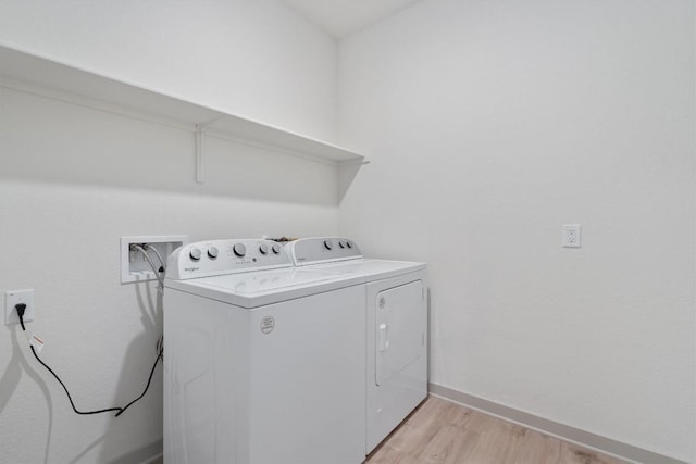 clothes washing area featuring laundry area, baseboards, light wood finished floors, and washer and clothes dryer