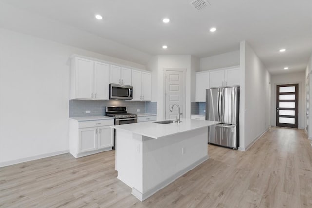 kitchen with sink, white cabinetry, stainless steel appliances, and an island with sink