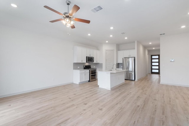 kitchen featuring tasteful backsplash, visible vents, open floor plan, light wood-type flooring, and stainless steel appliances