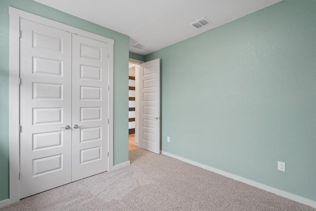 unfurnished bedroom with carpet, visible vents, a closet, and baseboards