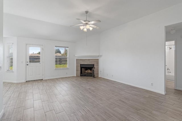 unfurnished living room featuring ceiling fan, lofted ceiling, and a tiled fireplace