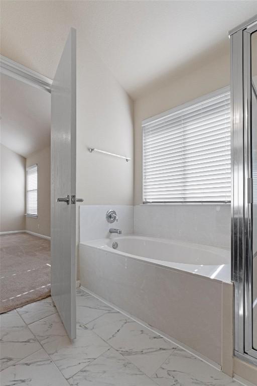 bathroom with a bath and vaulted ceiling