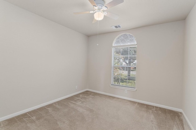 carpeted empty room with a wealth of natural light and ceiling fan