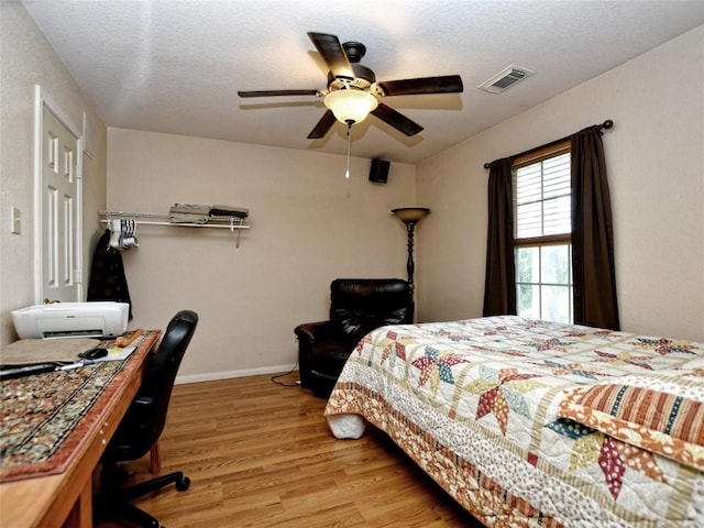 bedroom with a textured ceiling, light hardwood / wood-style floors, and ceiling fan