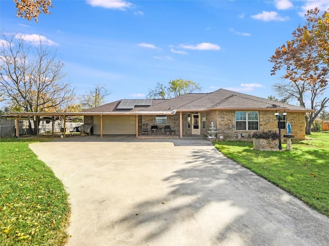 ranch-style home featuring a carport, solar panels, and a front lawn