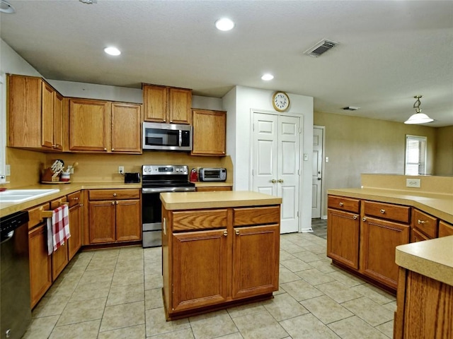 kitchen with light tile patterned flooring, sink, a kitchen island, and stainless steel appliances