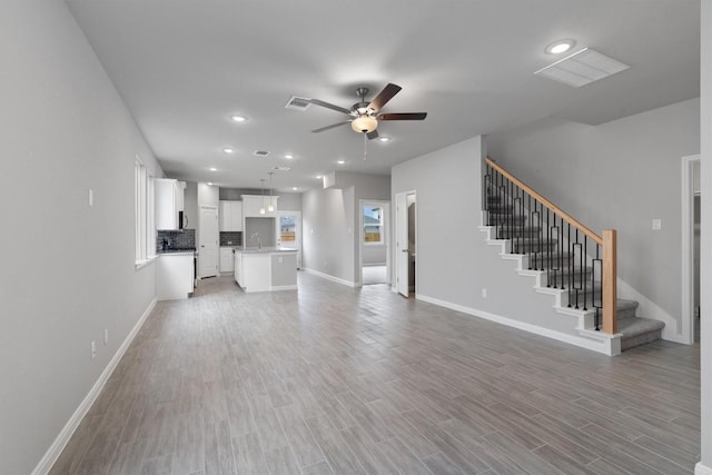 unfurnished living room with hardwood / wood-style floors, ceiling fan, and sink