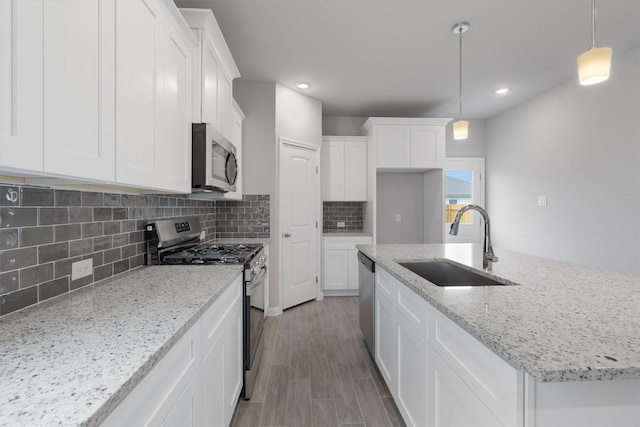 kitchen featuring pendant lighting, sink, light stone countertops, appliances with stainless steel finishes, and white cabinetry