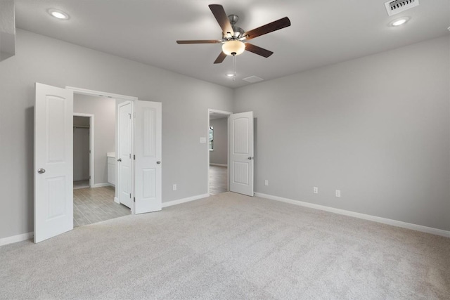 unfurnished bedroom featuring ceiling fan, light carpet, and a spacious closet