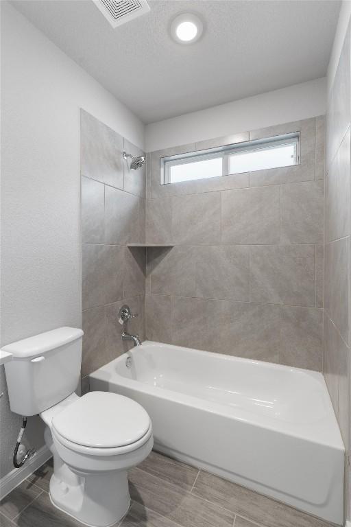 bathroom with tiled shower / bath combo and toilet