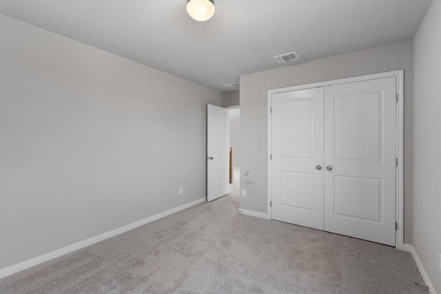 unfurnished bedroom featuring light colored carpet and a closet