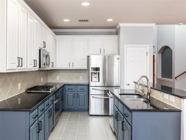 kitchen featuring white cabinets, appliances with stainless steel finishes, blue cabinets, and a sink