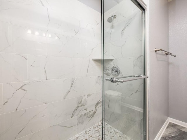 bathroom with a shower stall and baseboards